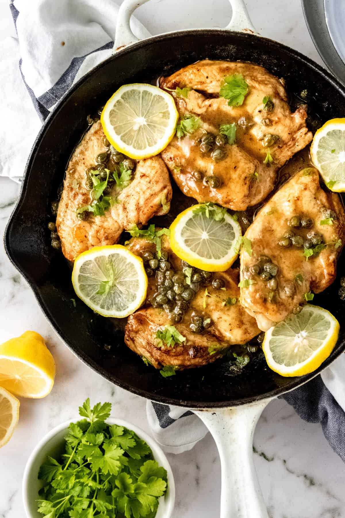 top down shot of chicken piccata with capers served in a cast iron skillet