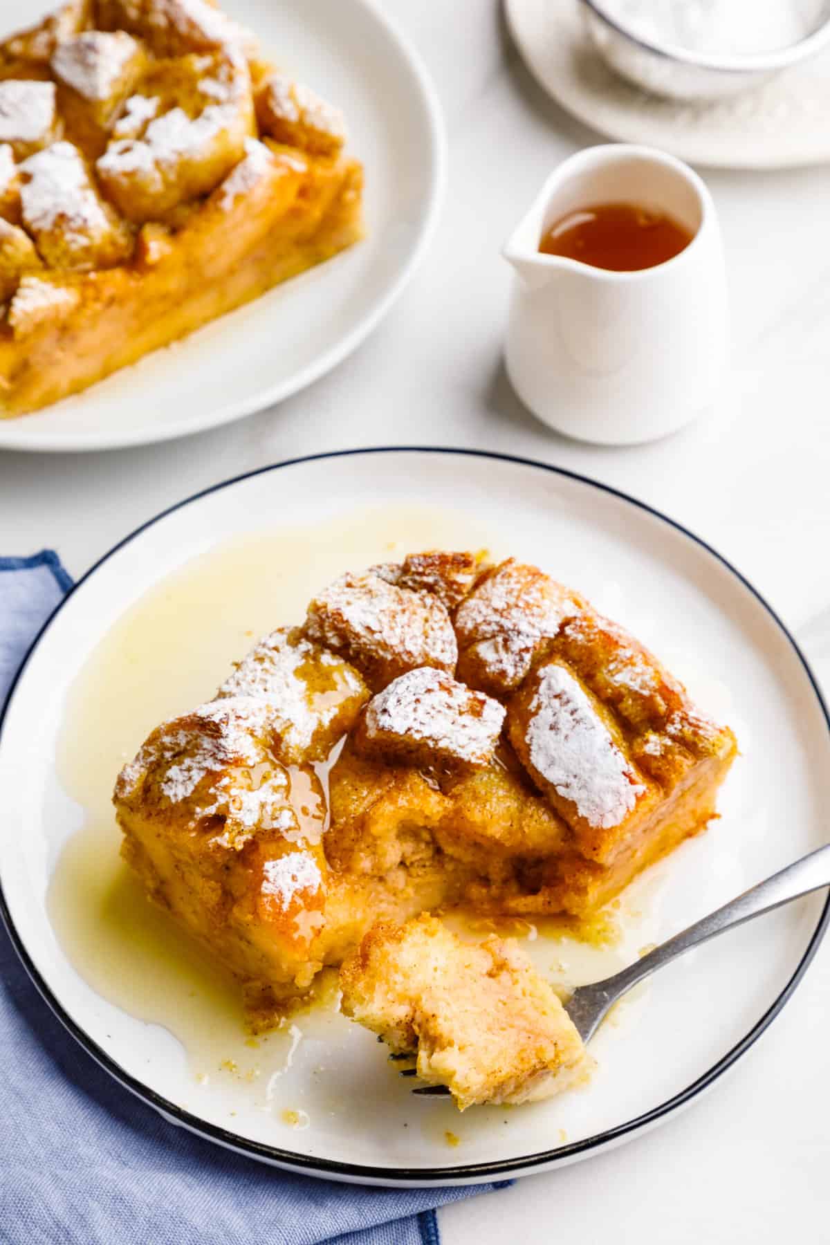 serving of pumpkin french toast casserole topped with syrup and powdered sugar served on a round plate