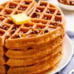 A stack of Bisquick pumpkin waffles topped with butter and syrup.