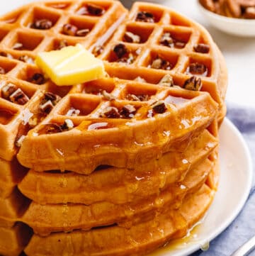 A stack of Bisquick pumpkin waffles topped with butter and syrup.