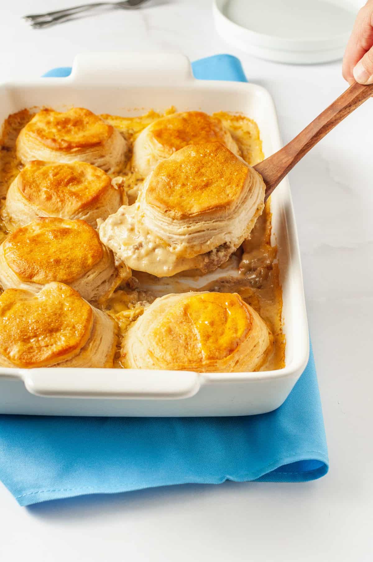 close up image of biscuits and gravy casserole sitting on a wooden spoon