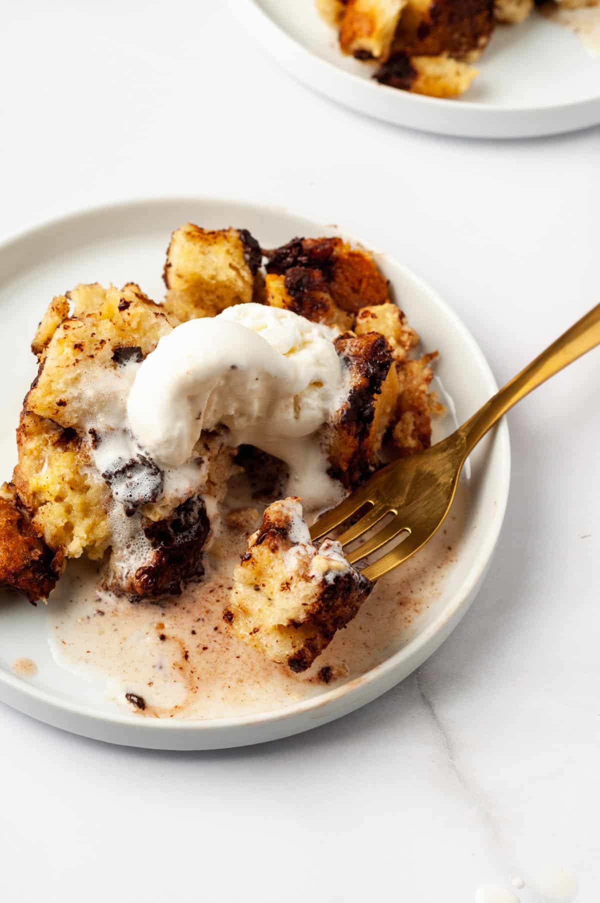 serving of chocolate chip bread pudding made from a slow cooker served on a white round plate with a gold fork