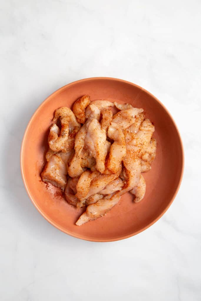 Seasoned raw chicken in bowl.