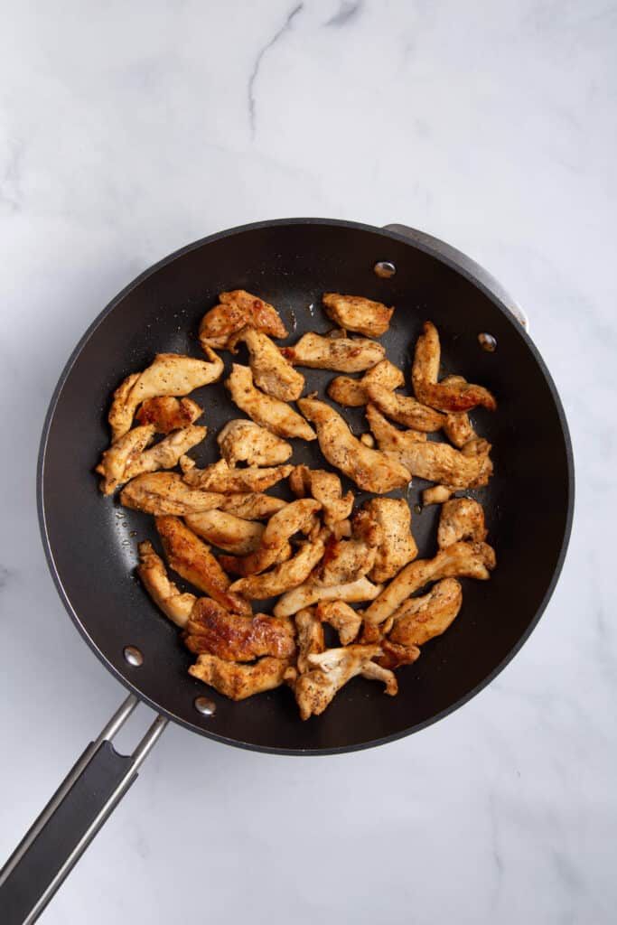 Chicken cooking in skillet.