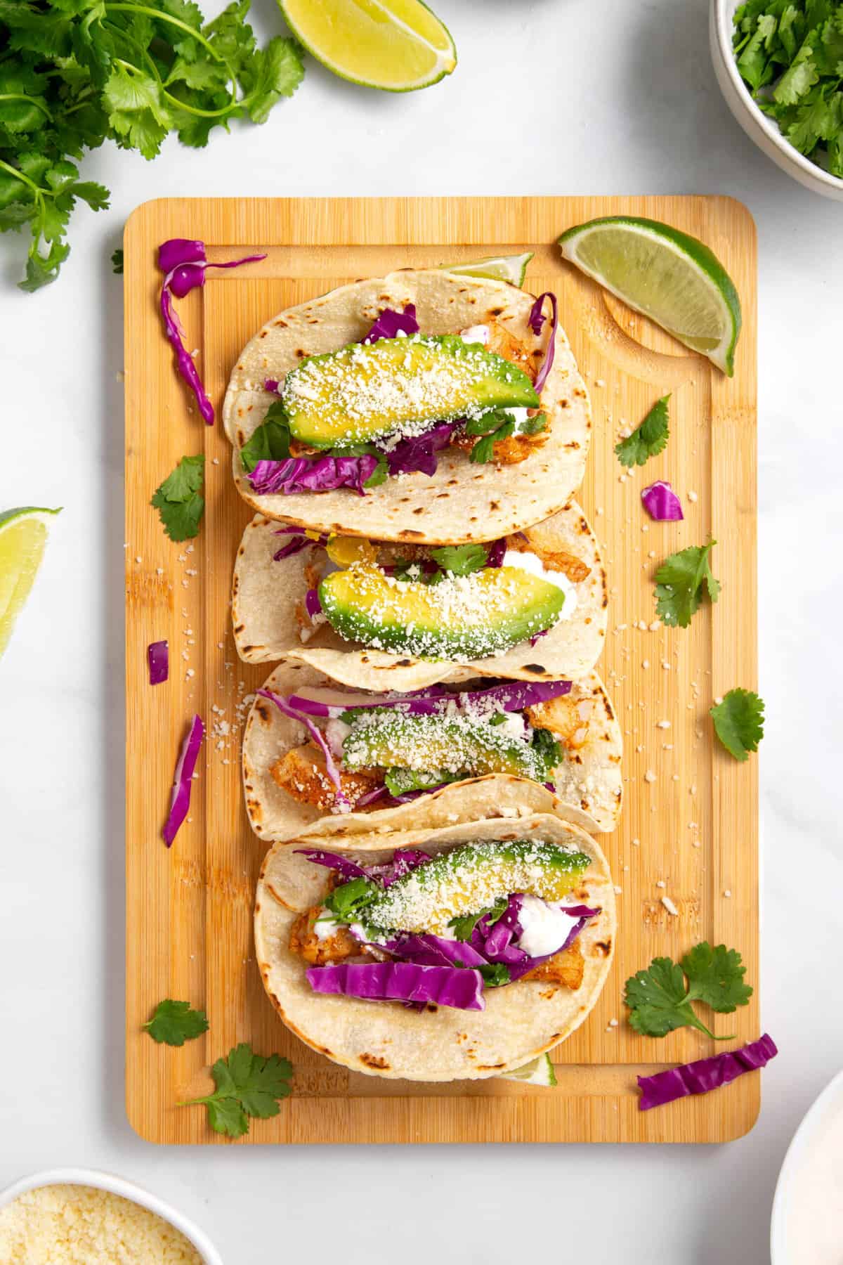 top down image of four fish tacos served on a wooden board