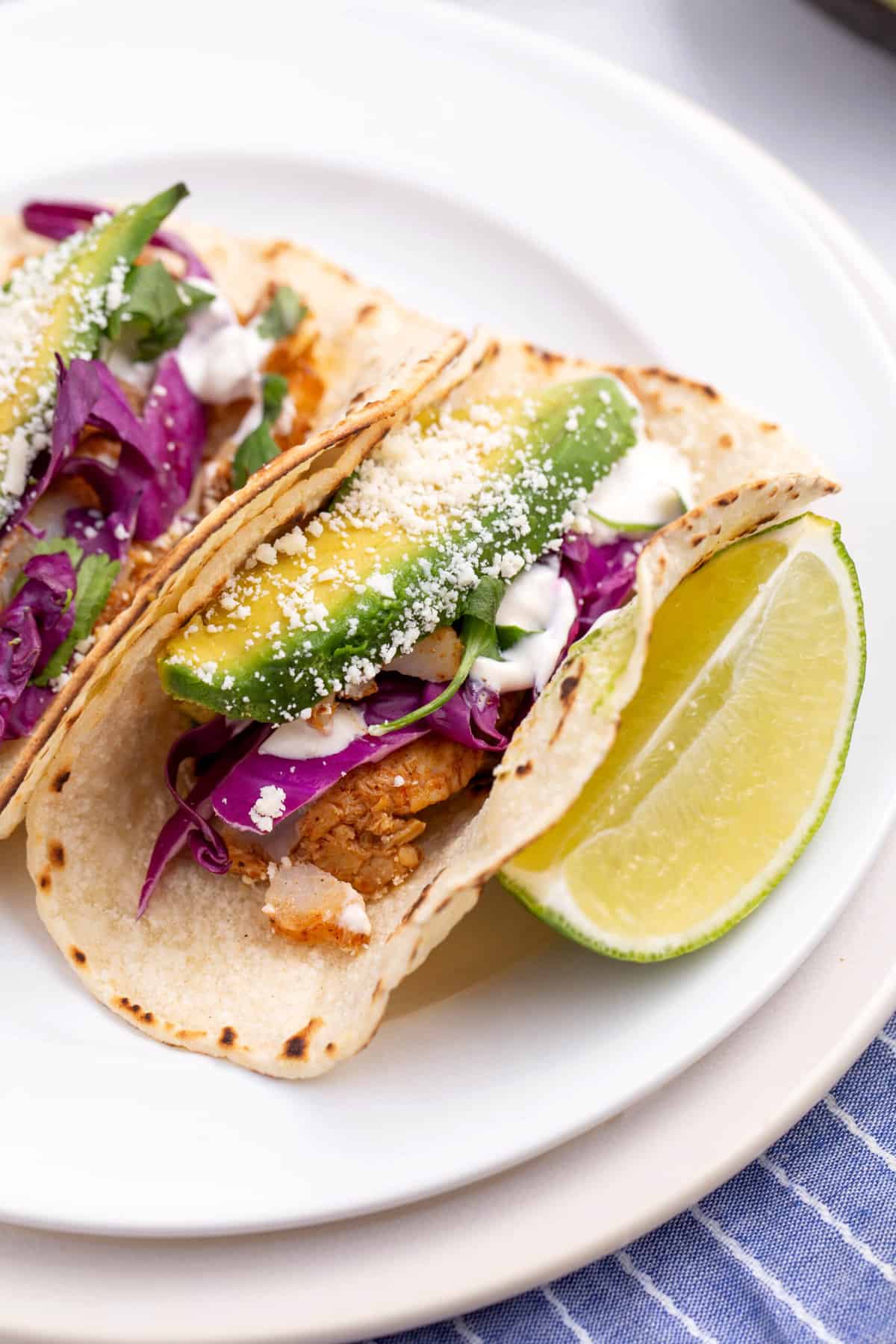 close up image of a fish taco served on a white round plate