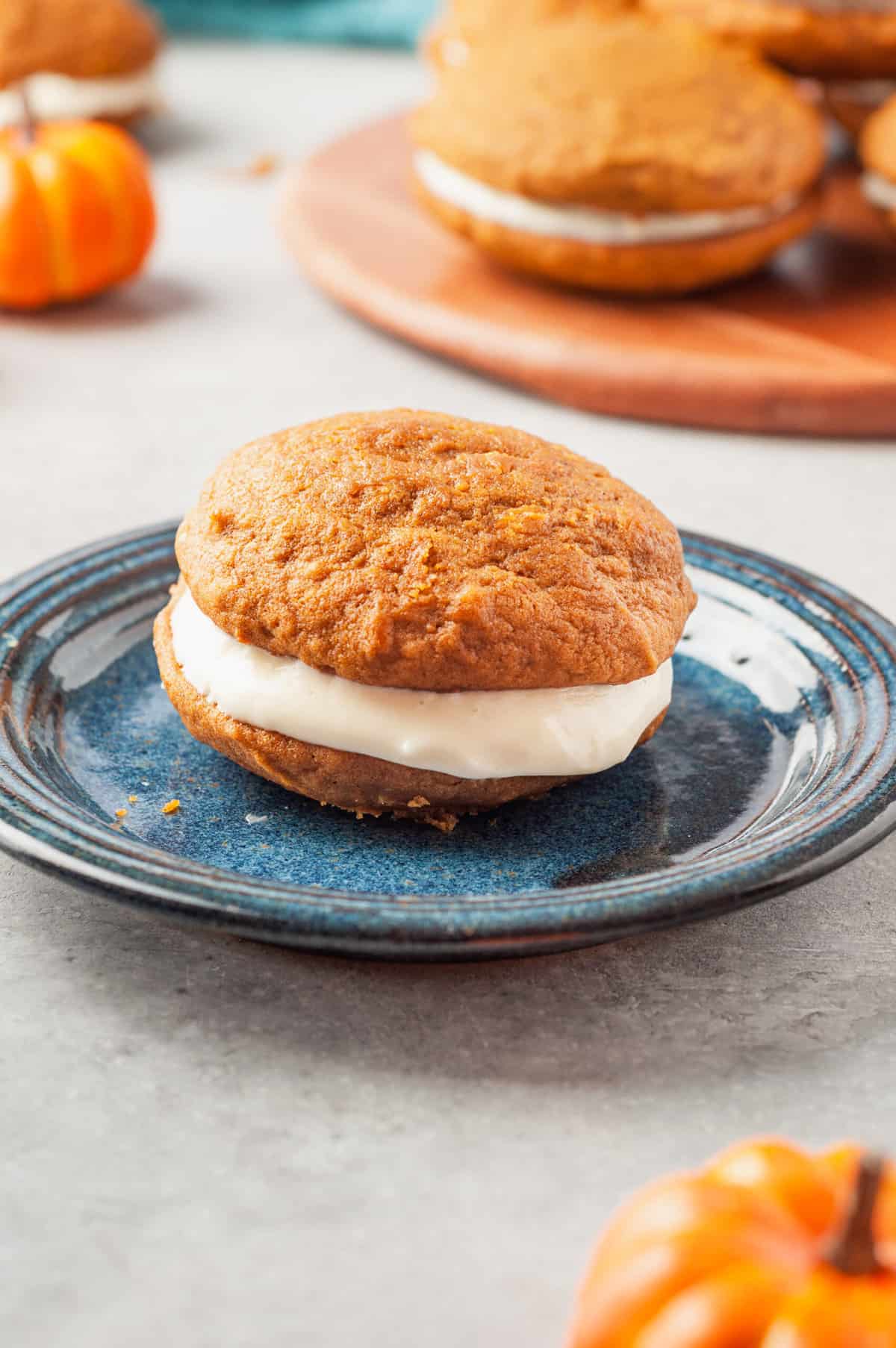 side view angle shot of a pumpkin whoopie pie sitting on a dark blue round plate