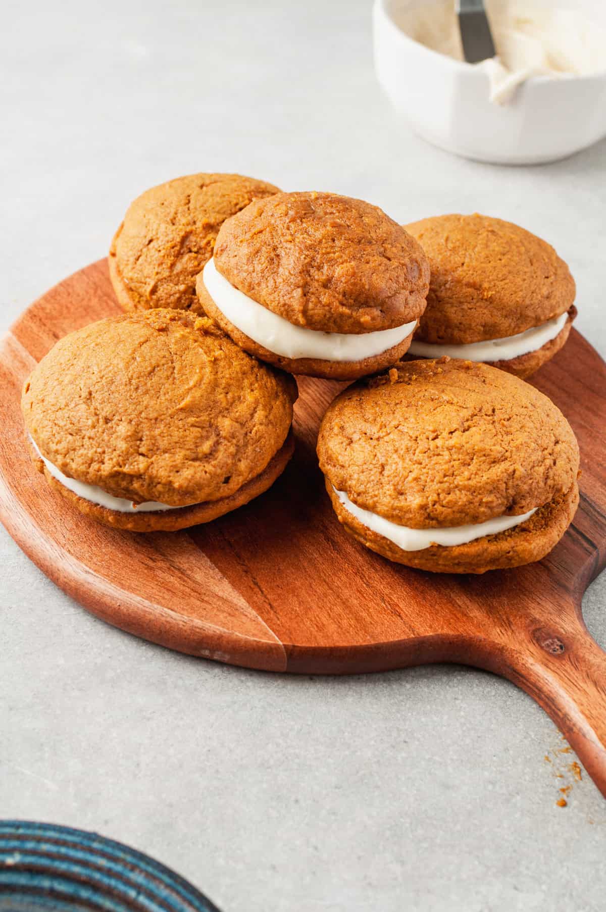 stack of five pumpkin whoopie pies served on a wooden board with a handle