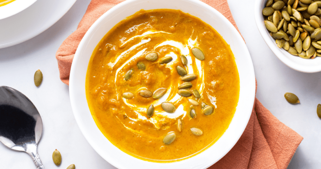A bowl of pumpkin soup topped with pepitas.
