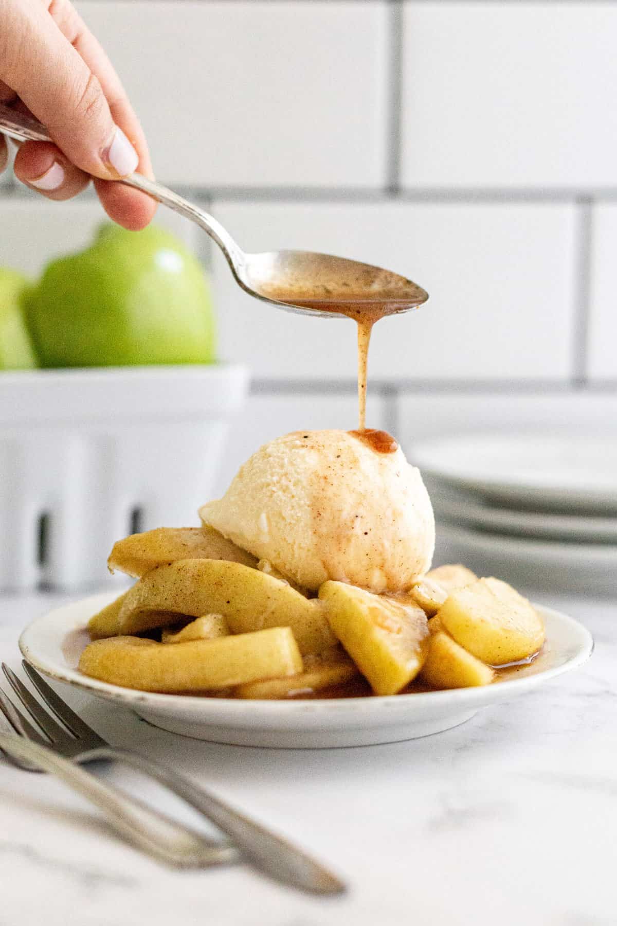 syrup poured on top of friend apples with a scoop of french vanilla ice cream served on a white plate
