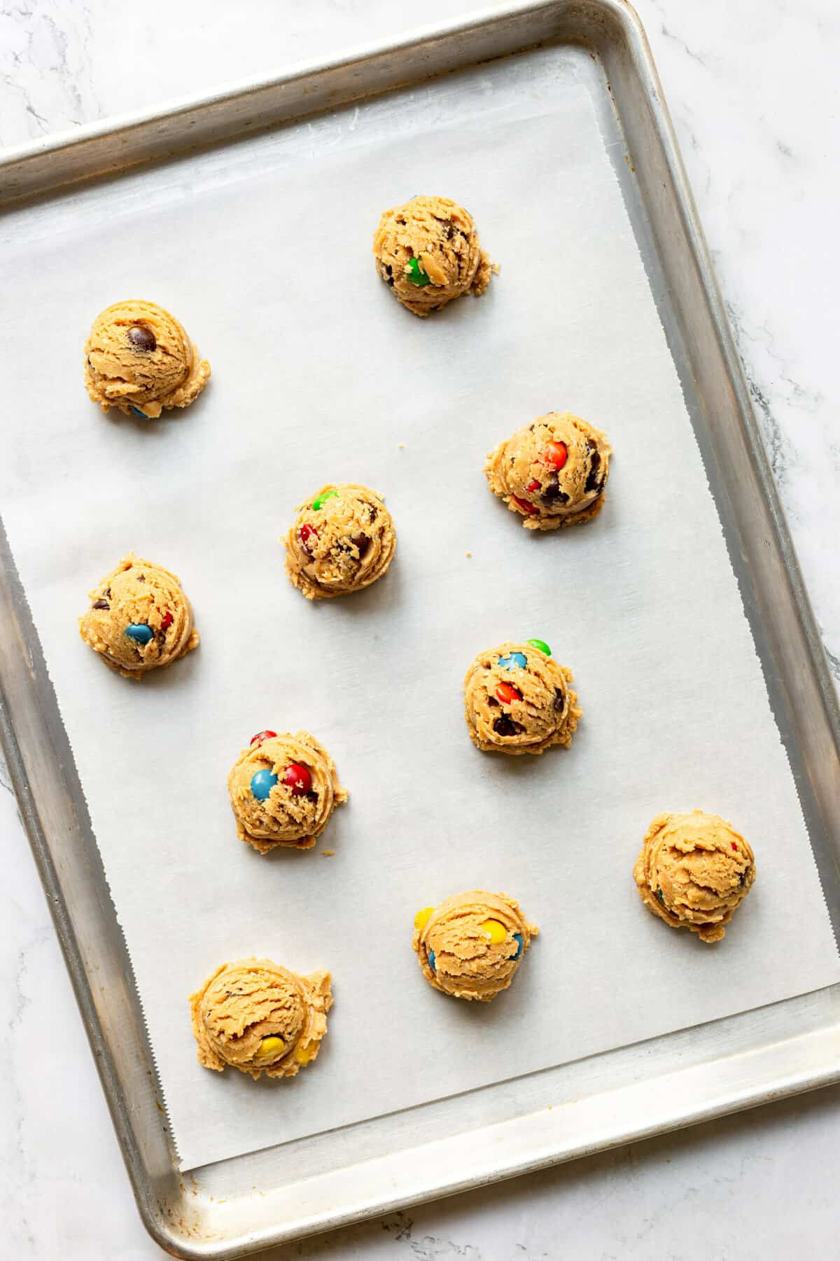 monster cookie dough sitting on a parchment-lined baking sheet