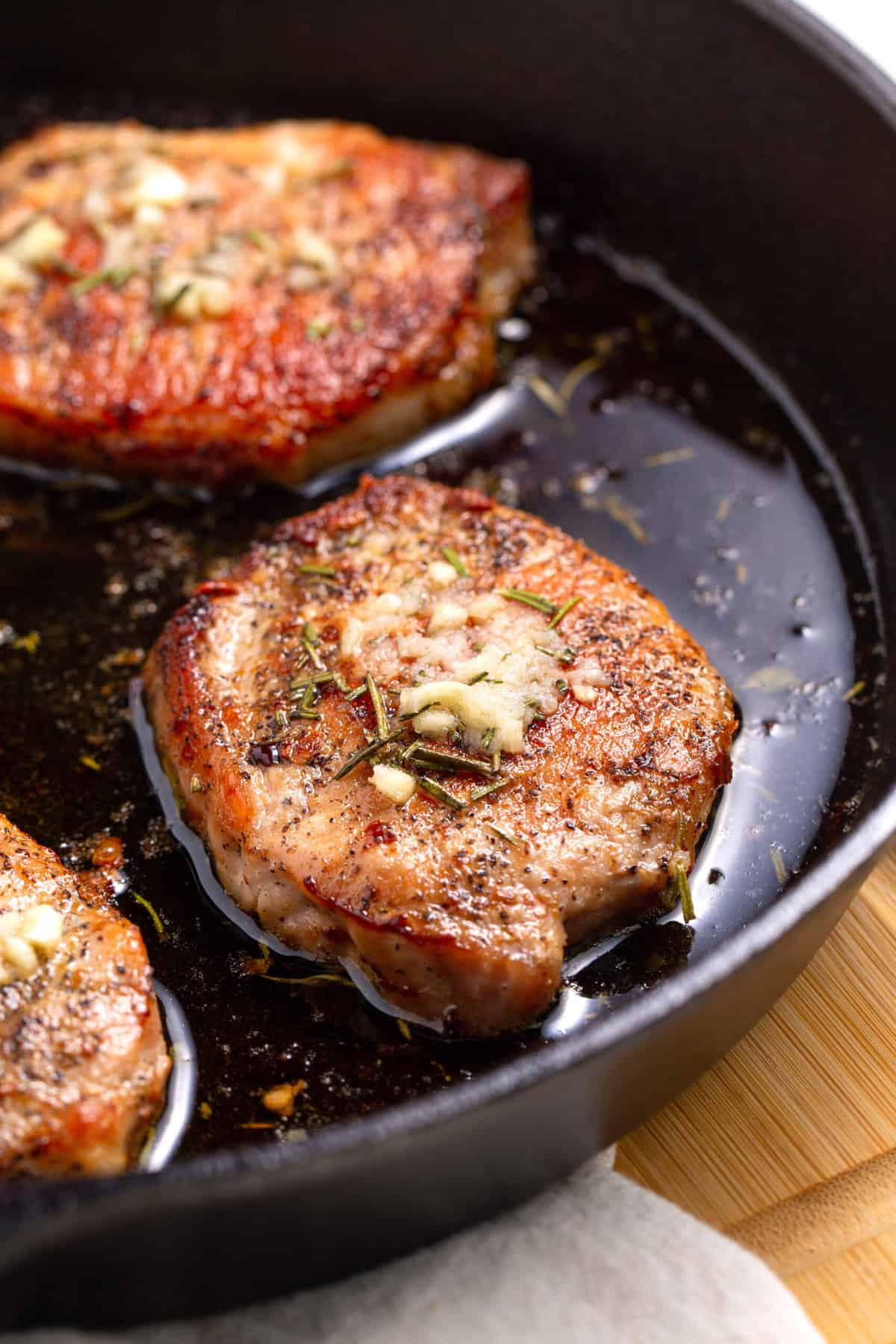 close up image of a baked pork chop served in a cast iron skillet