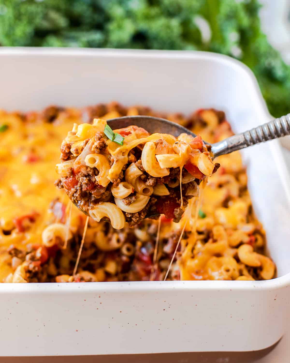 close up image of cheeseburger casserole on a metal serving spoon.