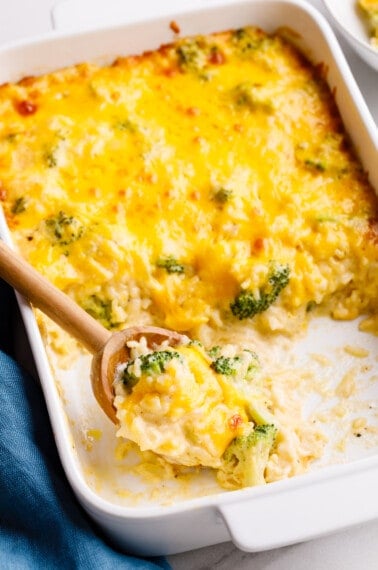 Cheesy broccoli rice casserole in a baking dish with servings missing.