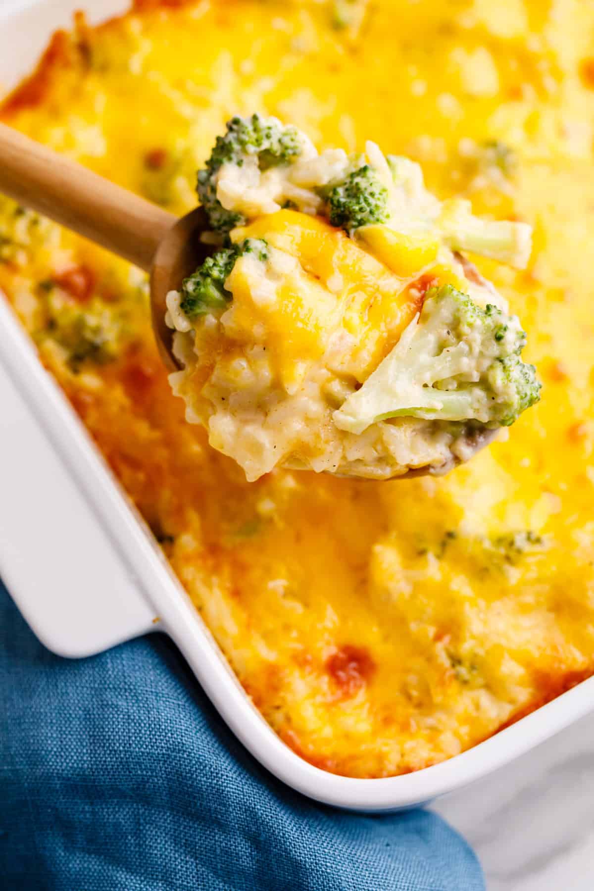 close up wooden spoonful of cheesy broccoli rice casserole