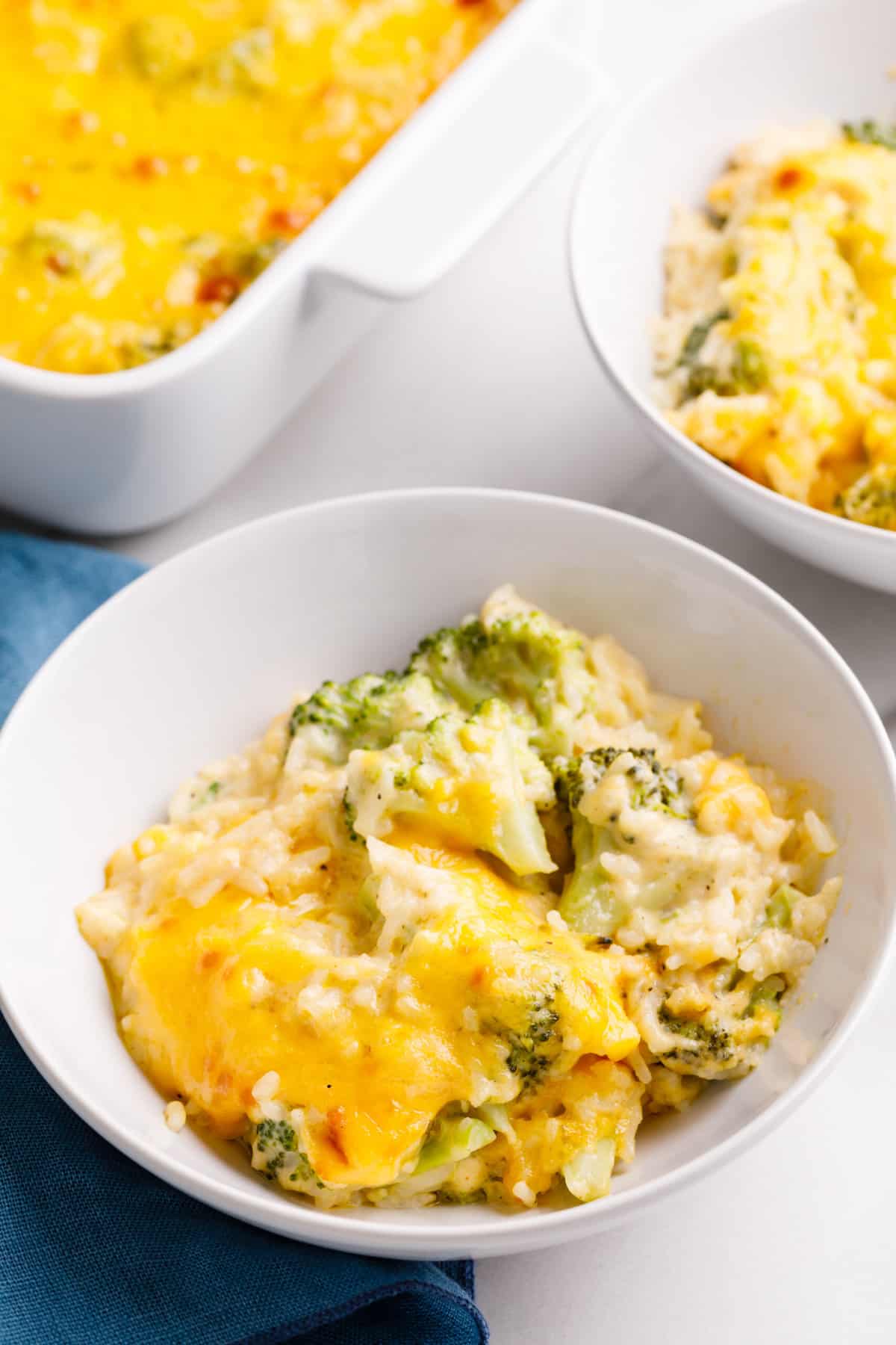 serving of cheesy broccoli rice casserole served in a white round bowl.
