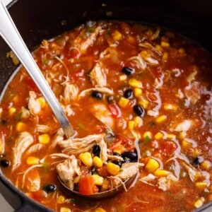 A ladle lifting a scoop of chicken tortilla soup from a pot.