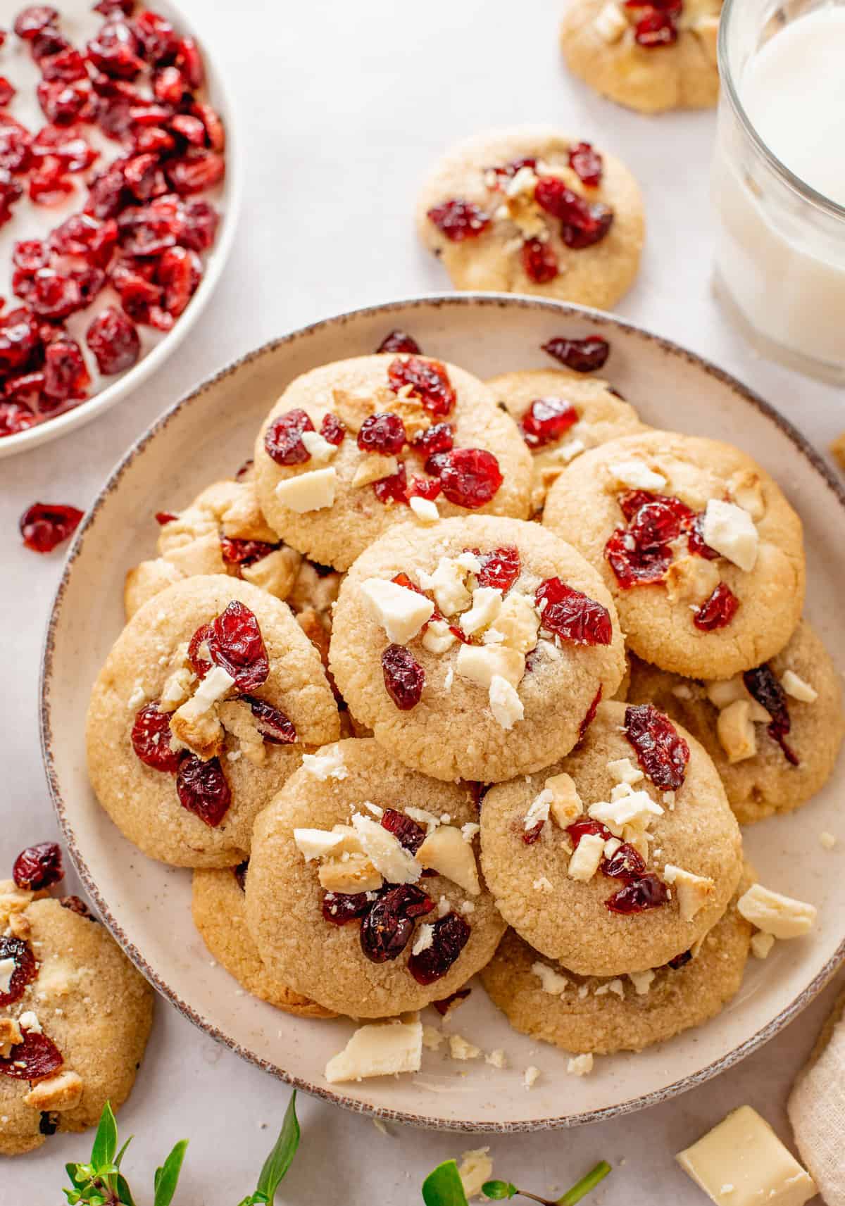 cranberry white chocolate chip cookies stacked and served on a round beige plate