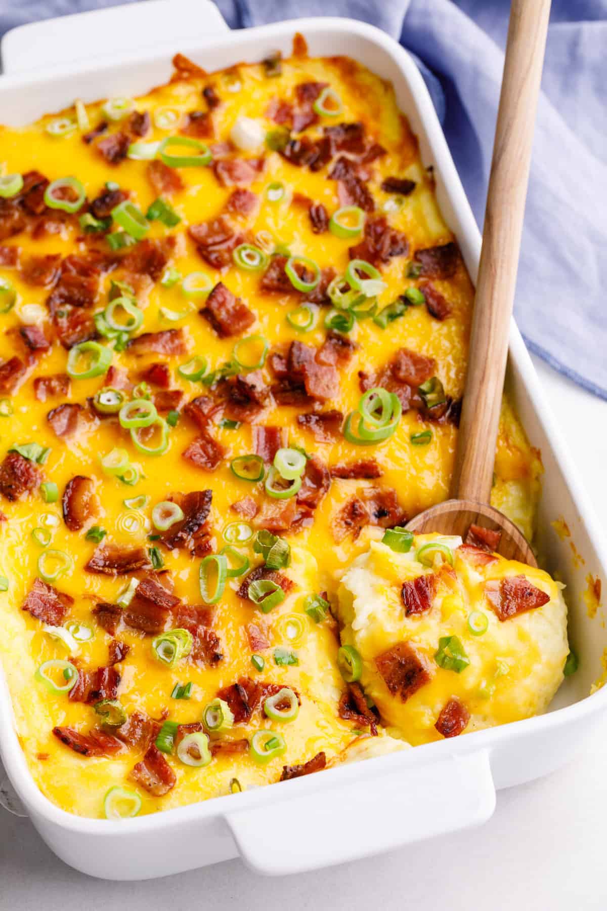 make-ahead potato casserole served in a casserole pan with a wooden spoon