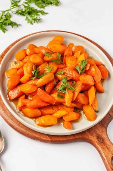 A plate full of honey glazed carrots topped with thyme.