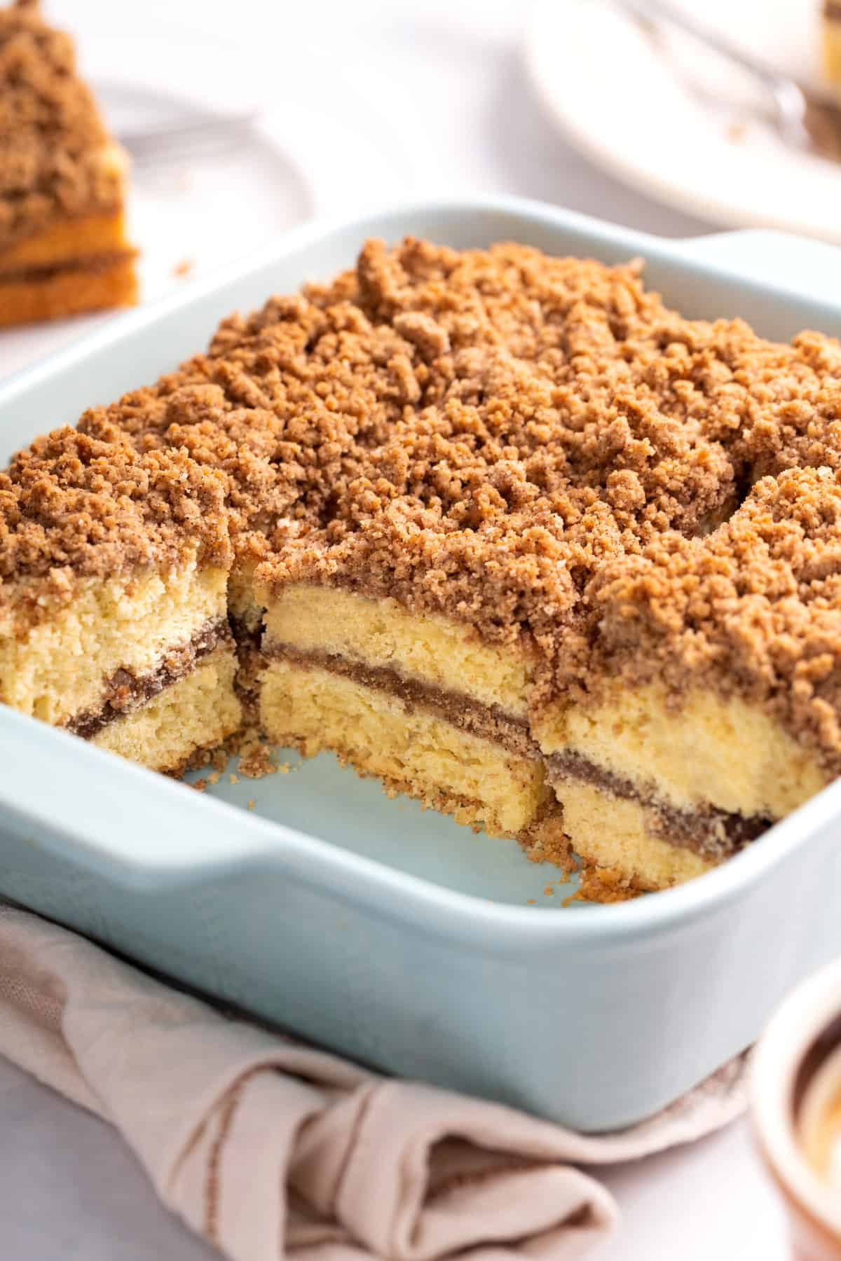 sliced coffee cake served in a blue 9x9 inch baking dish to show the cross section.