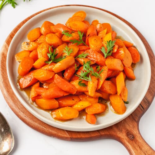 A plate full of honey glazed carrots topped with thyme.