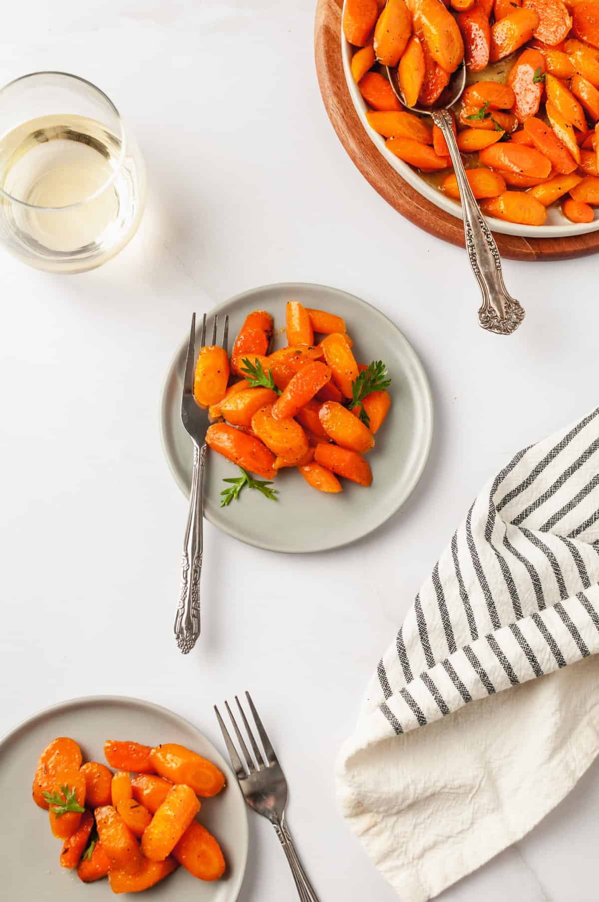 top down image of honey glazed carrots served on a grey round plate with a silver fork