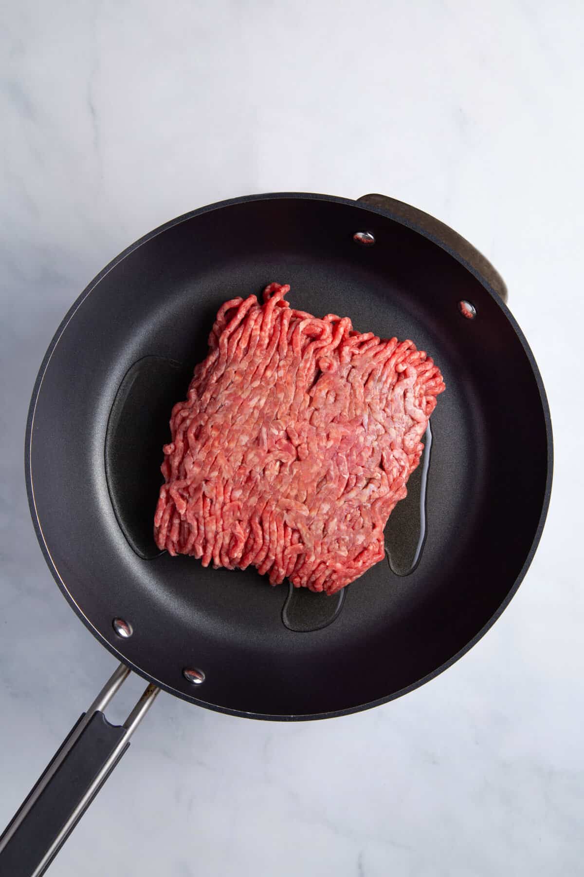 raw ground beef in a pan with oil.