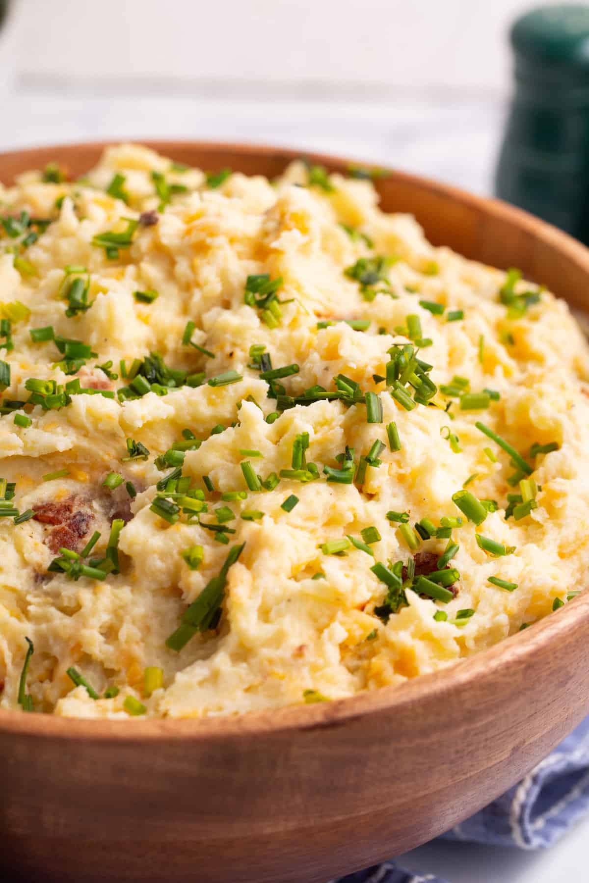 close up image of a wooden bowl full of loaded mashed potatoes