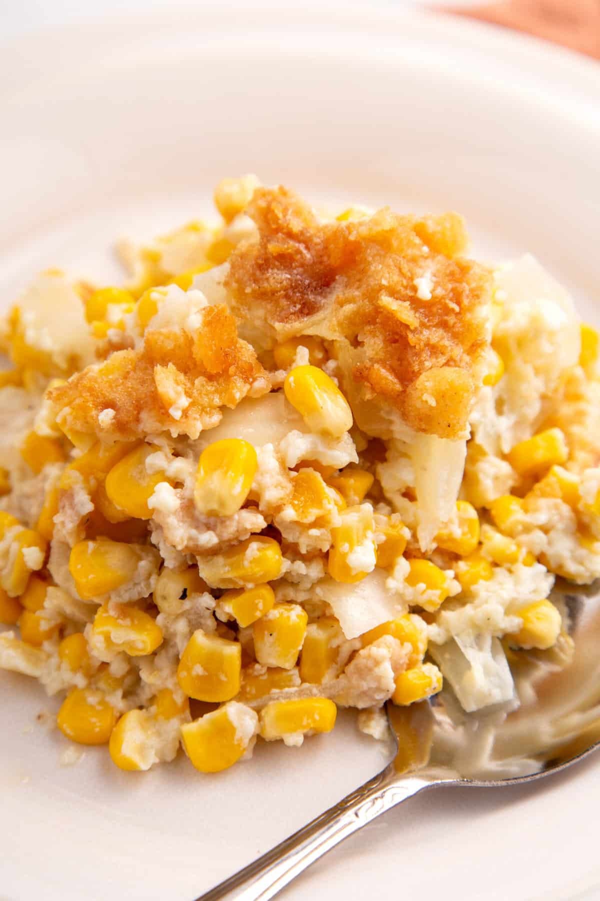 plate of scalloped corn with a silver spoon