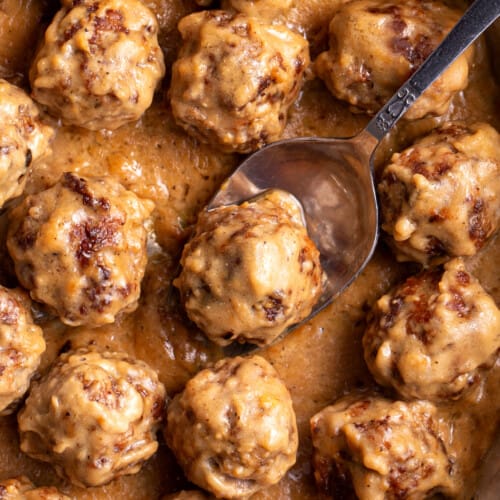 Swedish meatballs in a skillet with a spoon lifting one.