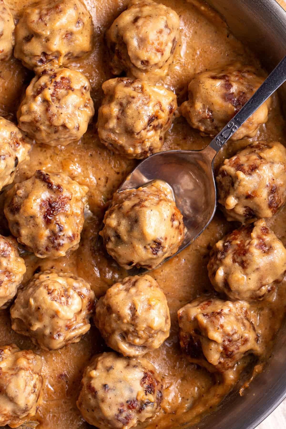 close up image of Swedish meatballs with gravy served in a stainless steel pan.