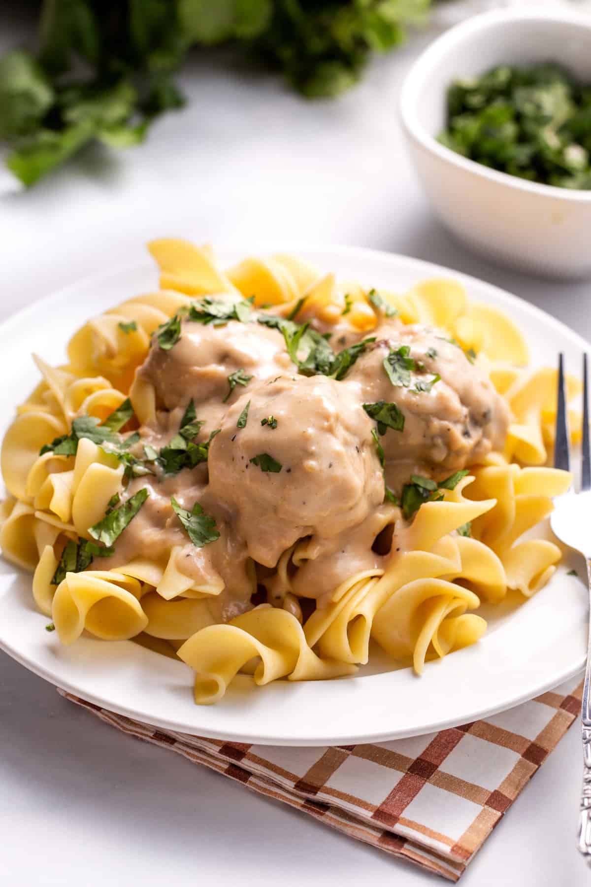 plate of Swedish meatballs sitting on a bed of cooked egg noodles.