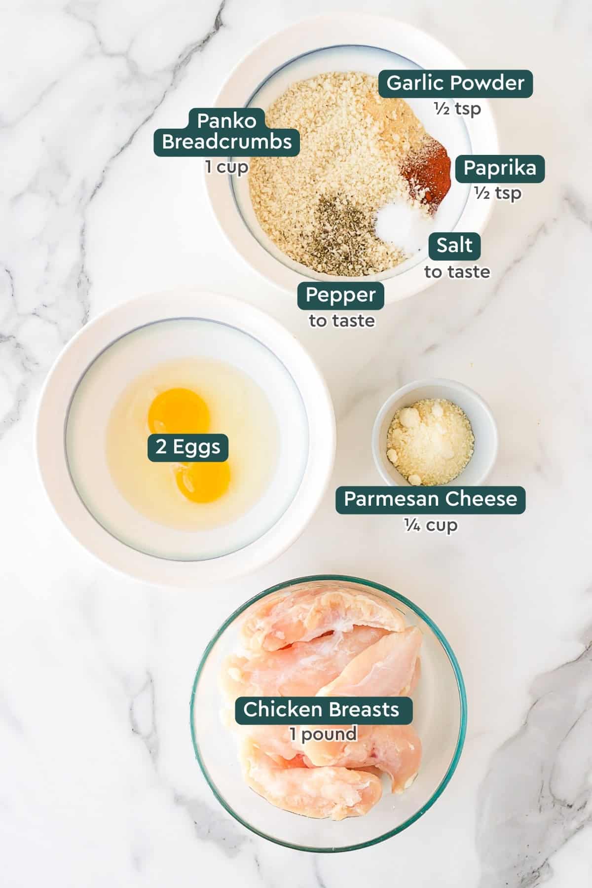 Ingredients for crispy chicken strips, including seasonings, panko, parmesan, eggs, chicken.