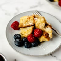 Crockpot French toast on a plate topped with strawberries and blueberries.