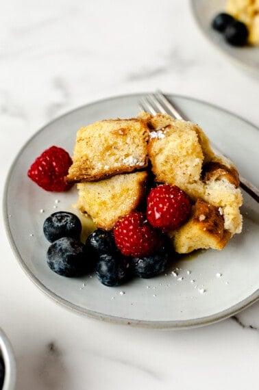 Crockpot French toast on a plate topped with strawberries and blueberries.