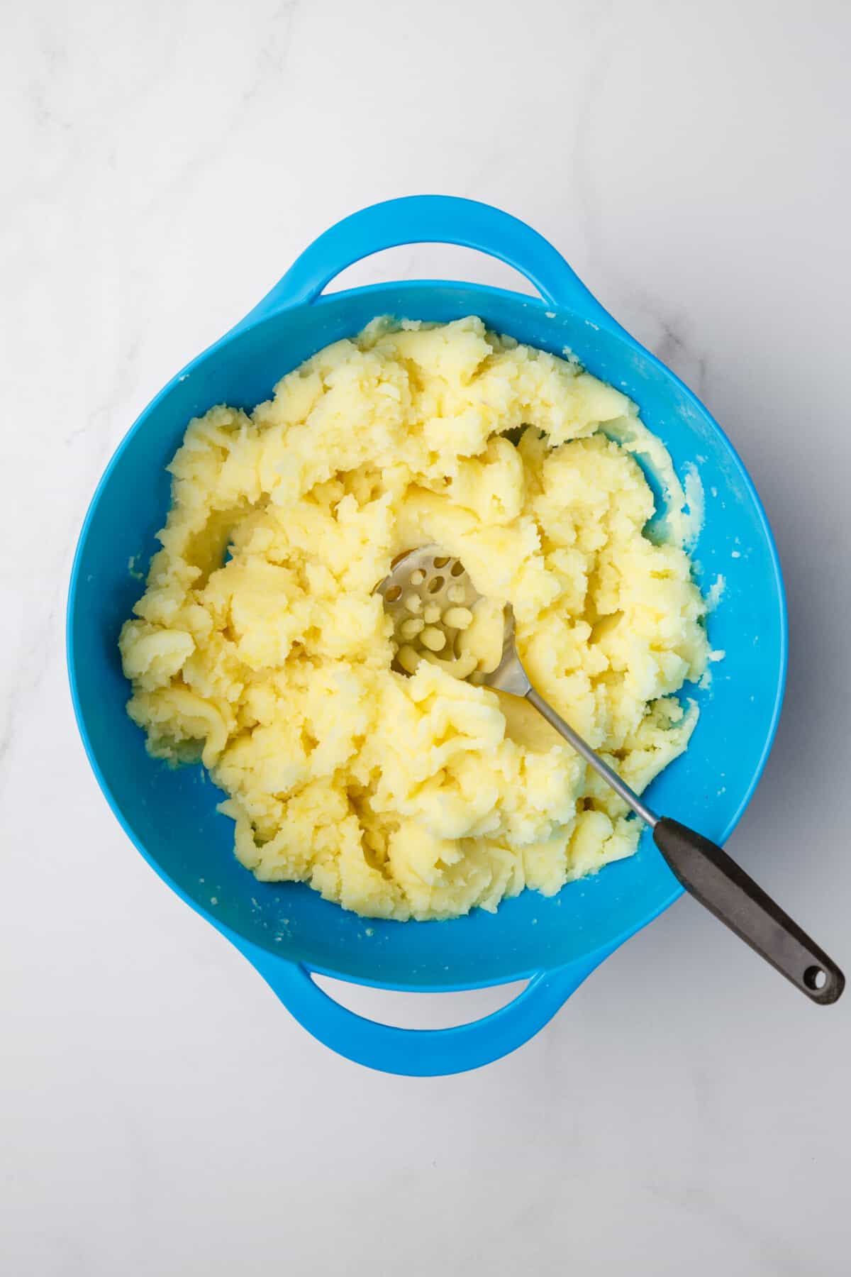 Mashing potatoes in large bowl.