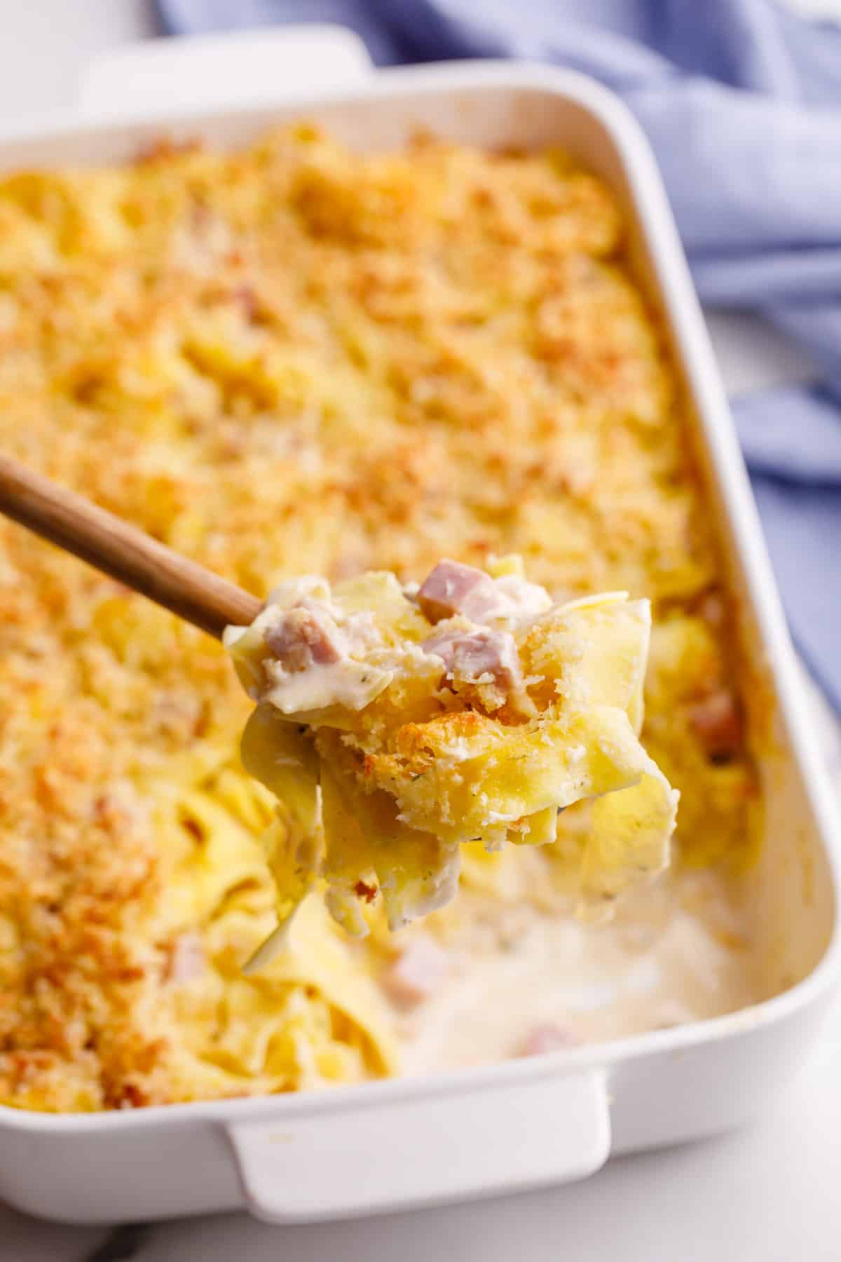 close up image of leftover ham casserole on a wooden spoon 