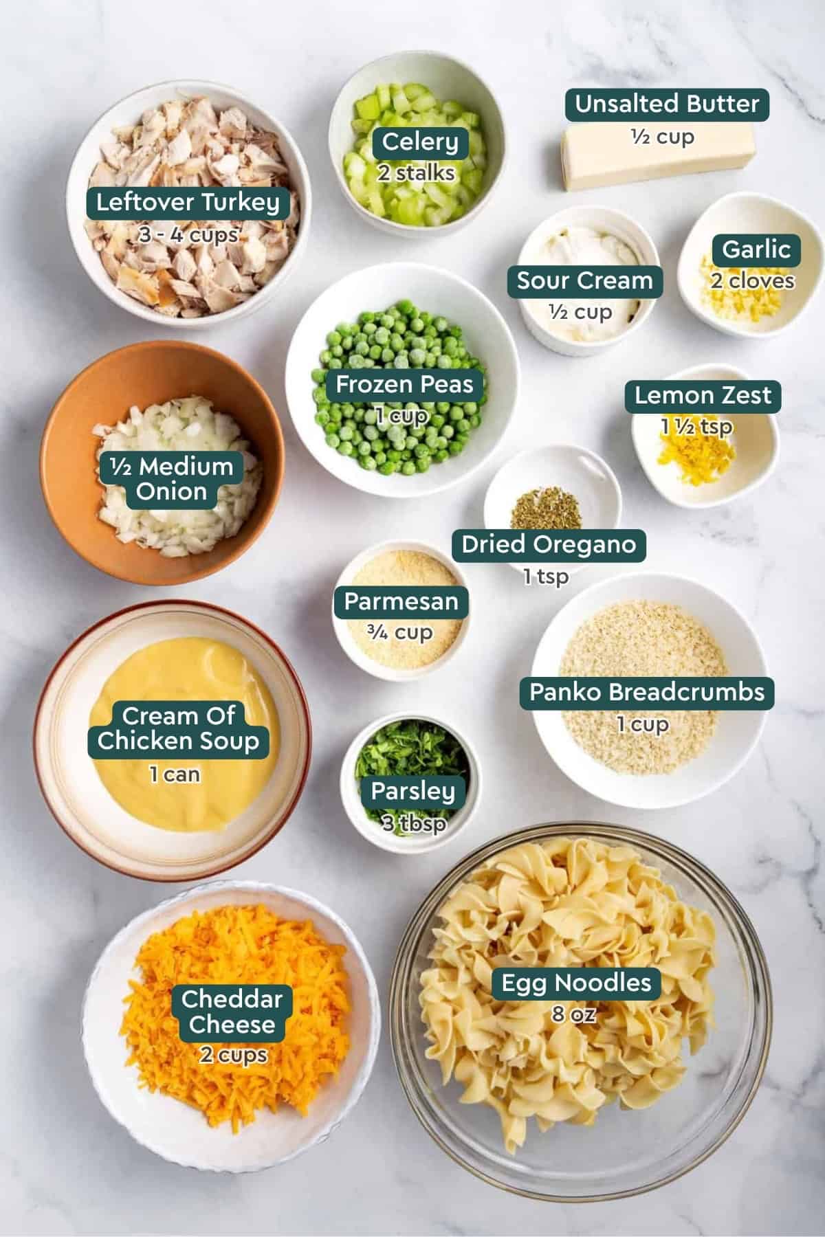 All of the ingredients for leftover turkey casserole in bowls on a white countertop.