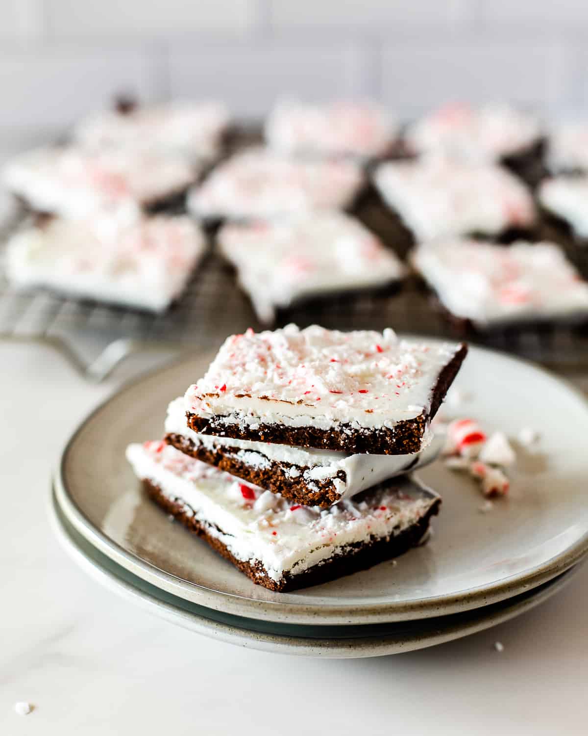 stack of peppermint bark brownies served on two stacked grey plates