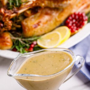 Turkey gravy in front of a roasted Thanksgiving turkey.