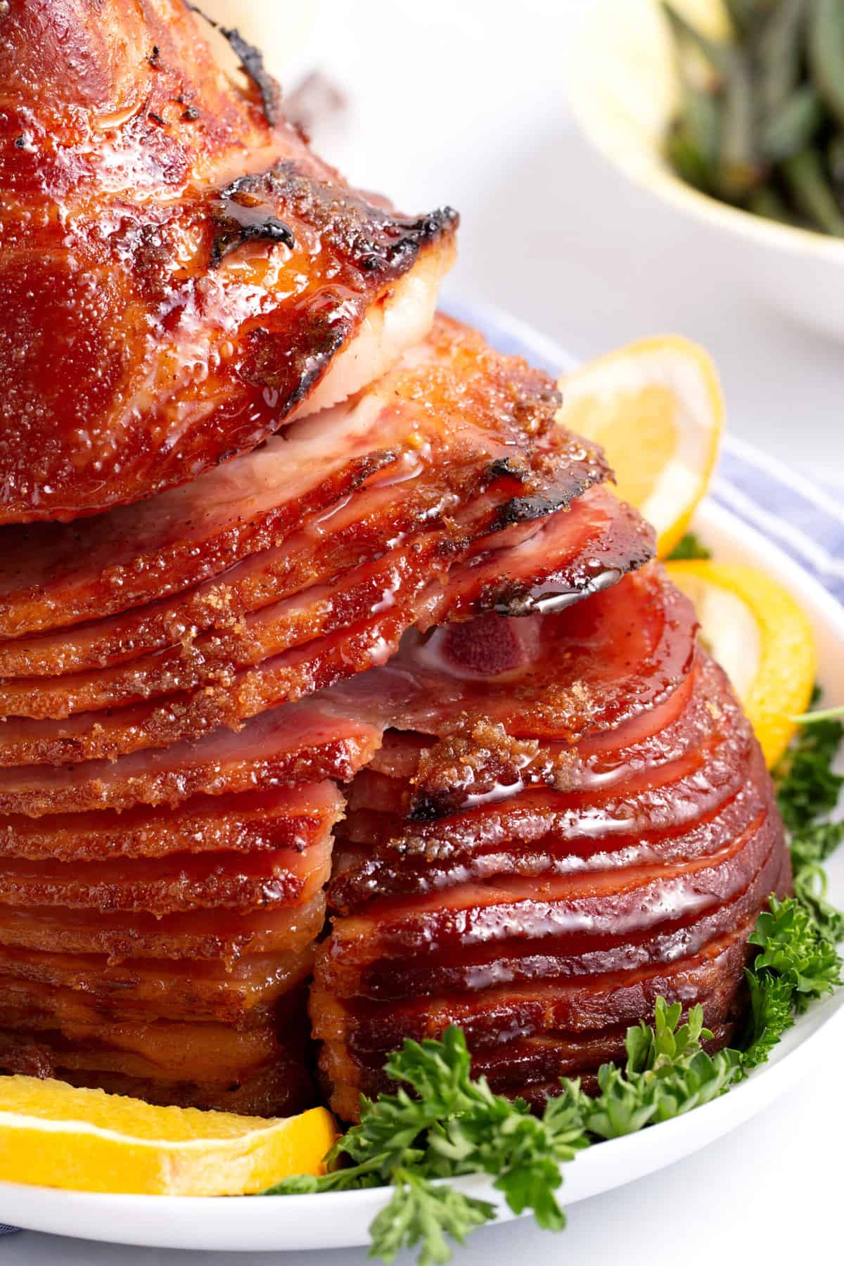 close up image of sliced honey baked ham served on a bed of greens and sliced lemons