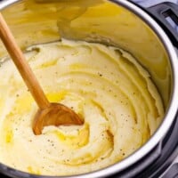 Instant Pot mashed potatoes being stirred with a wooden spoon.