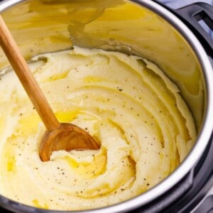 Instant Pot mashed potatoes being stirred with a wooden spoon.