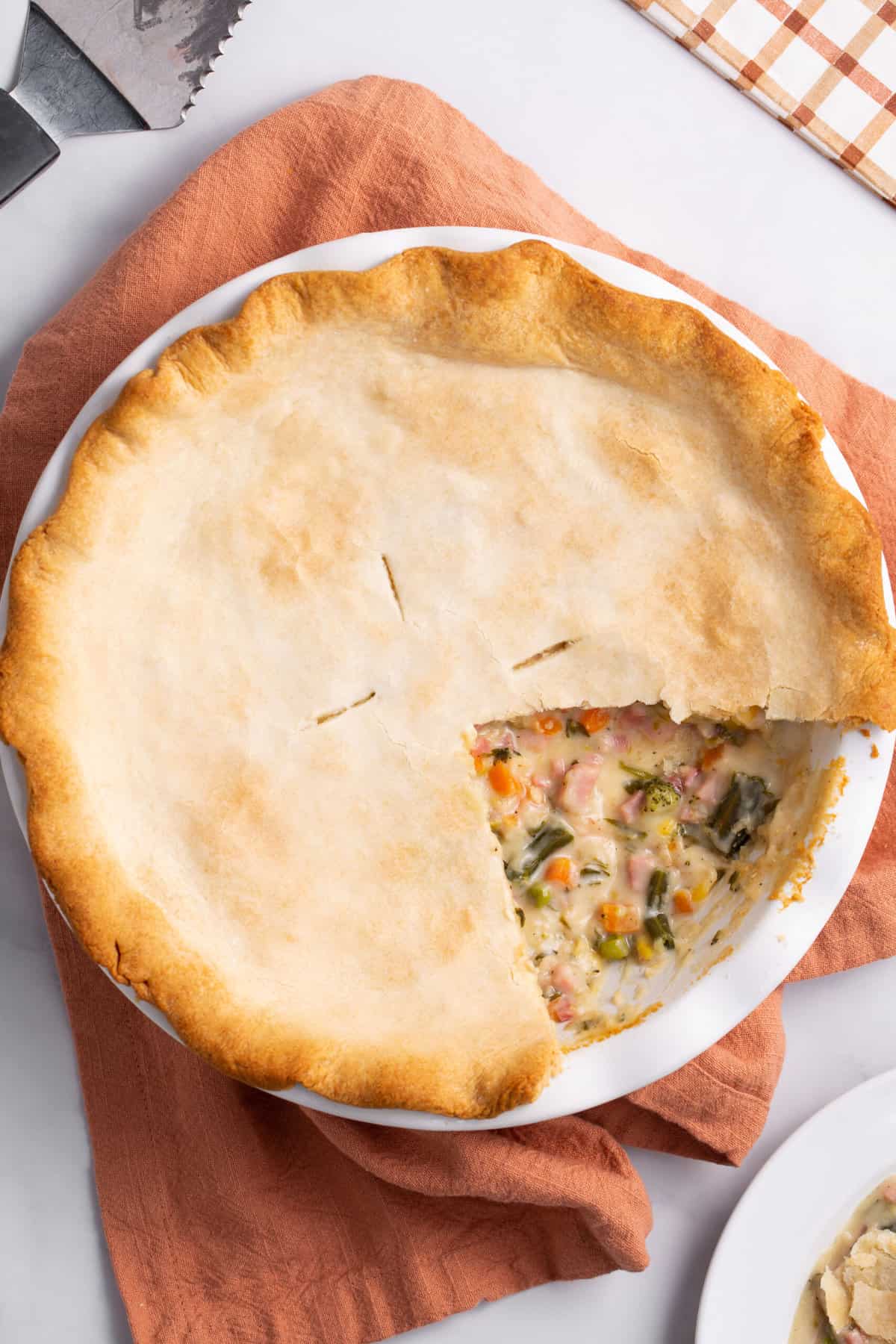 top down image of hot ham pie served in a pie dish with a slice cut out to show the interior