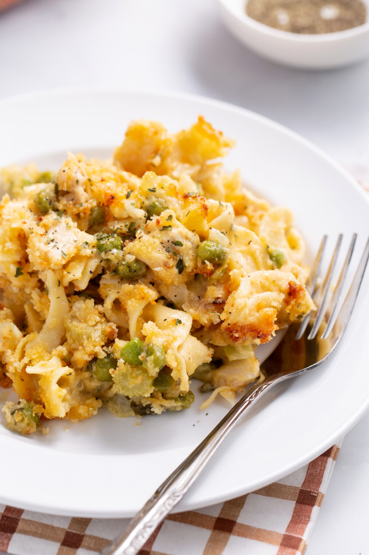 Leftover turkey casserole on a white plate with a fork on the edge.