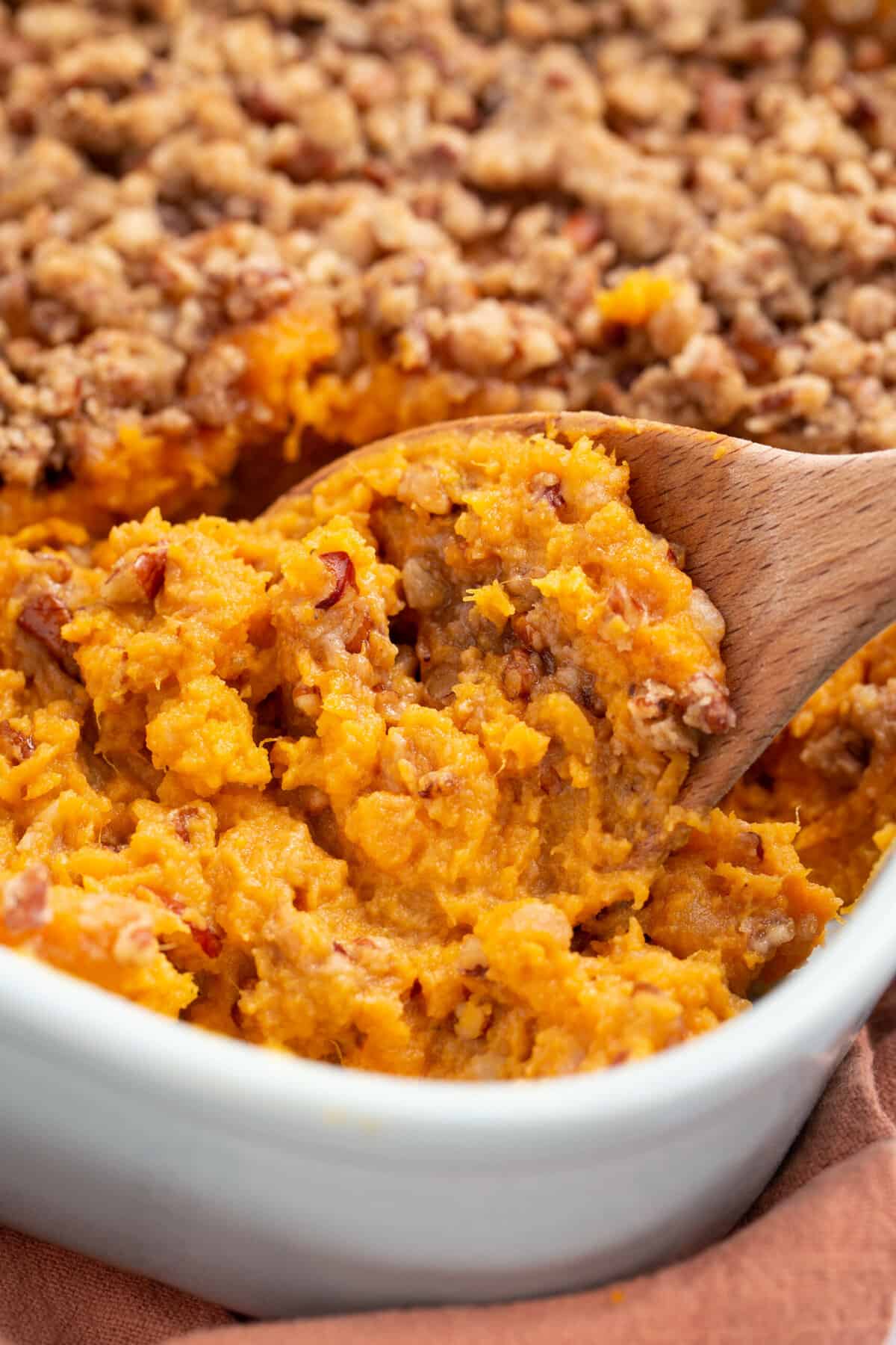 close up image of wooden spoon digging into yam casserole