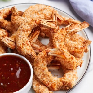 A plate of air fryer coconut shrimp with a side of chili sauce.