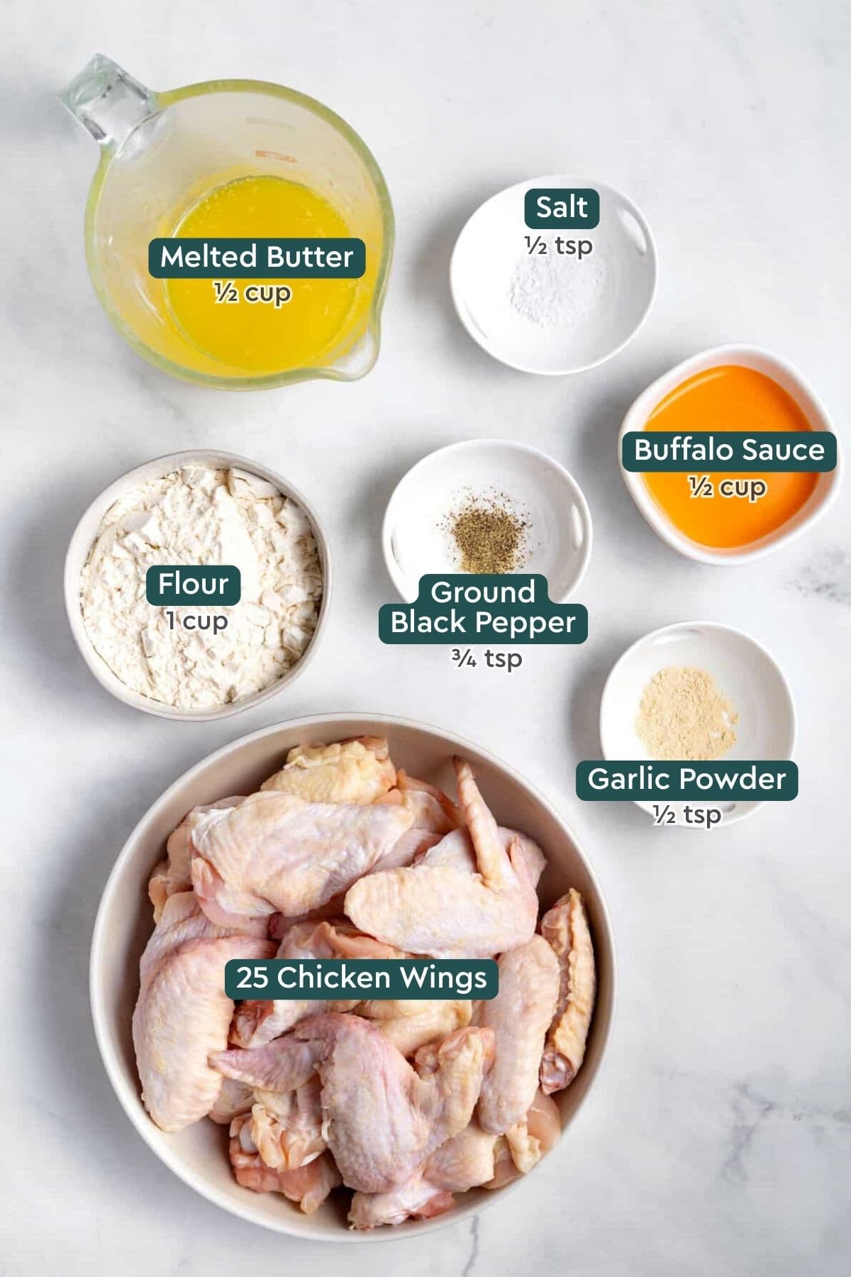 All of the ingredients for baked buffalo wings in bowls on a white countertop.