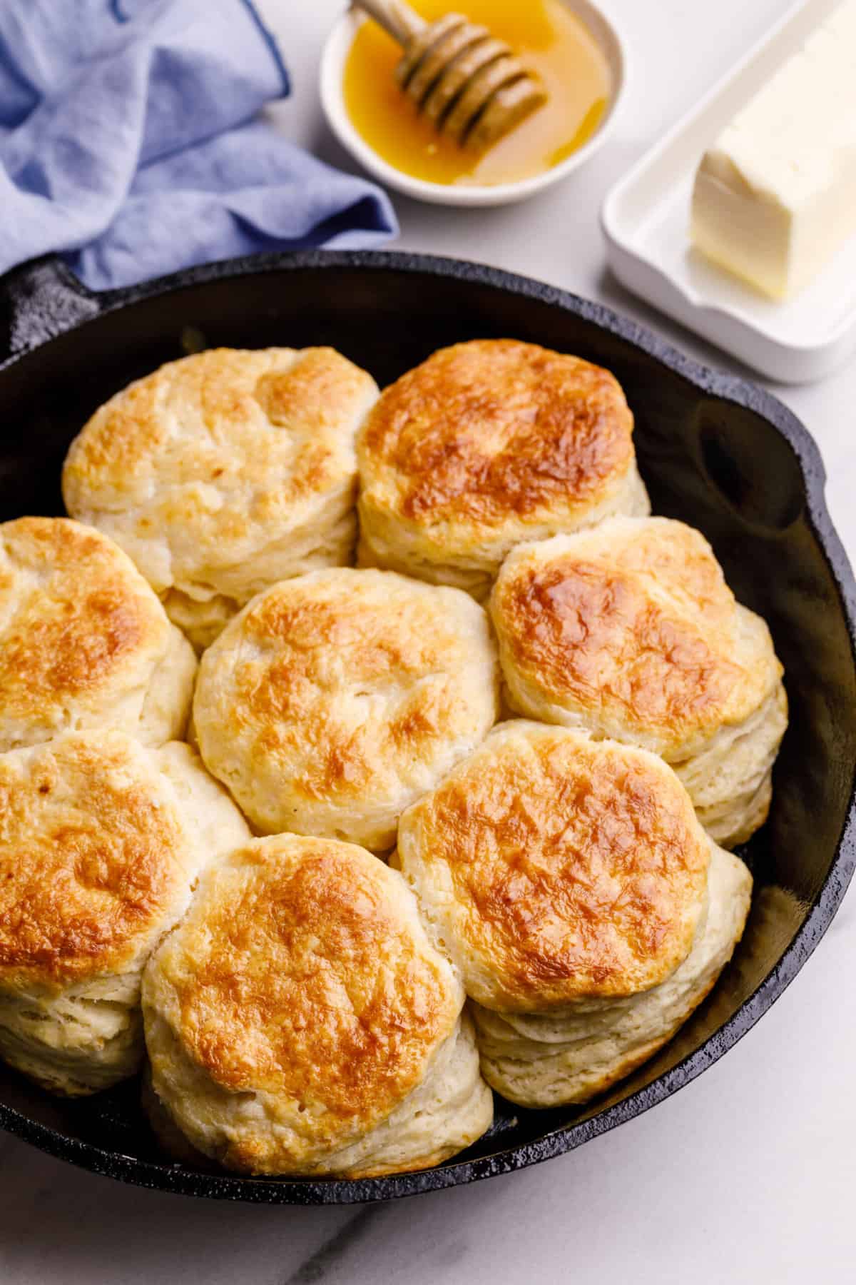 Baked buttermilk biscuits are shown sitting in a cast iron skillet.